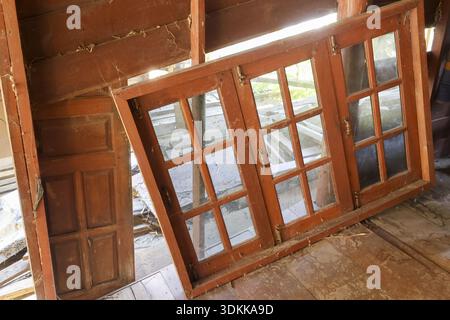 Il vecchio telaio della finestra in legno polveroso si appoggia in un attico rustico. pezzi di legno e vetro dimenticati negli interni della vecchia casa creano un'atmosfera tranquilla e nostalgica Foto Stock