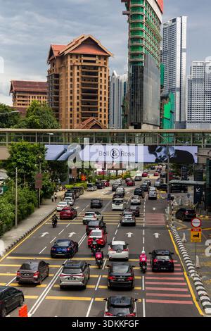 Un'animata scena stradale che mostra auto e motociclette che attraversano il quartiere di Bukit Bintang Foto Stock