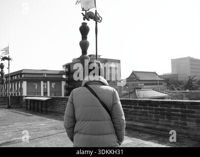 Foto in bianco e nero di una figura solitaria in cima alle mura della città di Xi'an Foto Stock