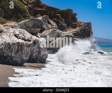 Un paesaggio con una costa rocciosa mediterranea vicino alla spiaggia di preveli a Creta, dove le onde si infrangono contro la costa Foto Stock