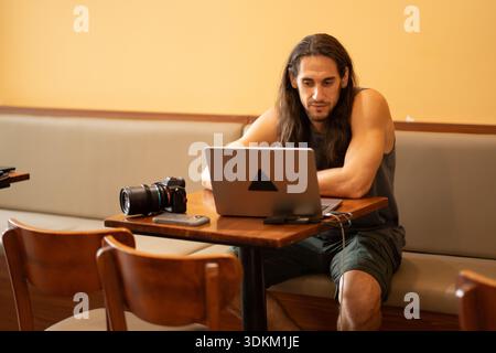 Nomade digitale maschile che lavora su un computer portatile in un bar Foto Stock