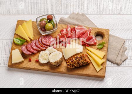 Formaggi assortiti e affettati su un tavolo di legno, piatto classico di antipasti per vino e riunioni Foto Stock