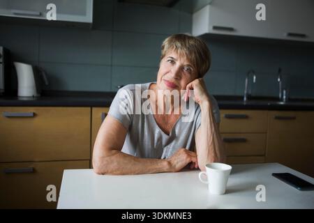 Portret donna anziana felice in cucina sta guardando la macchina fotografica. positivo. Concetto di stile di vita felice || modello rilasciato Foto Stock