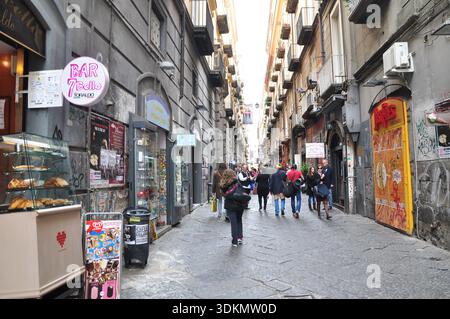 Pedoni che camminano lungo una stradina stretta nel centro storico di Napoli, Italia Foto Stock