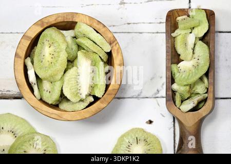 fette di kiwi liofilizzate in stoviglie in legno di oliva su fondo rustico in legno Foto Stock