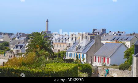 Una vista panoramica del villaggio con tradizionali case bianche, alte palme e un faro, adagiato su un cielo azzurro limpido sulla costa mediterranea. Foto Stock