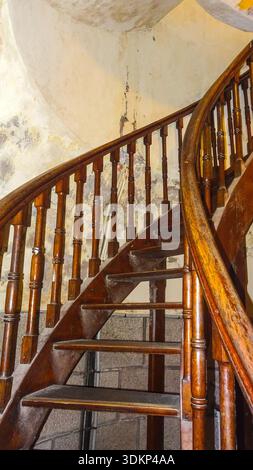 Primo piano di una scala a chiocciola in legno che mostra dettagli intricati e usurati e la bella consistenza del legno invecchiato. Foto Stock