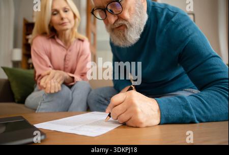 Coppia anziana che compila i documenti di firma del modulo che si siedono all'interno Foto Stock