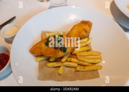 Pesce e patatine croccanti dorate servite un piatto bianco, classico cibo britannico, piatto da asporto a base di pesce isolato su sfondo pulito, piatto da ristorante! Foto Stock
