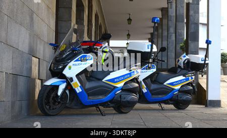 Puerto de la Cruz, Tenerife, 01152026 — due motociclette della polizia parcheggiate sotto un passaggio coperto in pietra, dotate di caschi, sirene e mezzi di comunicazione Foto Stock
