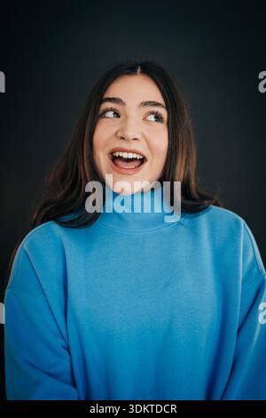 Giovane donna sorridente che guarda lontano con eccitazione Foto Stock
