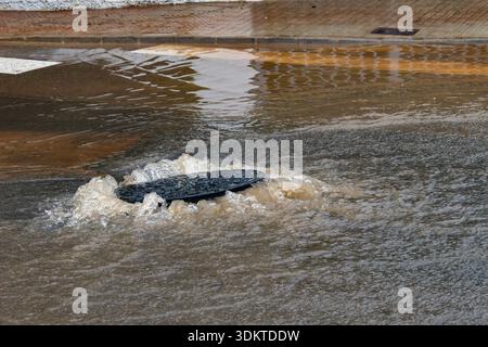 Strade urbane inondate di acqua che trabocca dagli scarichi quando le persone liberano le acque alluvionali e i veicoli si spostano attraverso le aree colpite dopo una pioggia intensa. Spagna. Foto Stock