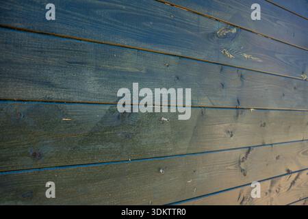 Una vista dettagliata di una parete in legno con tavole orizzontali con una finitura scura e resistente agli agenti atmosferici. La superficie mostra motivi di grana, nodi e imperf sottile Foto Stock