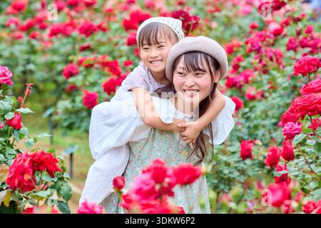 Madre che dà alla figlia un giro in un roseto Foto Stock