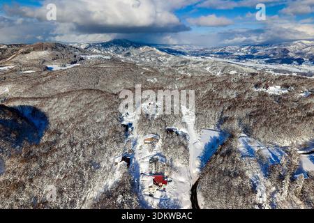Paesaggio invernale con case immerse in boschi innevati sullo sfondo delle montagne Foto Stock