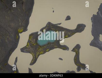 Vista aerea delle sabbie pallide che abbracciano una suggestiva piscina turchese, circondata da terreni scuri e accidentati, creando un paesaggio surreale e ultraterreno, Selfoss, ghiaccio Foto Stock