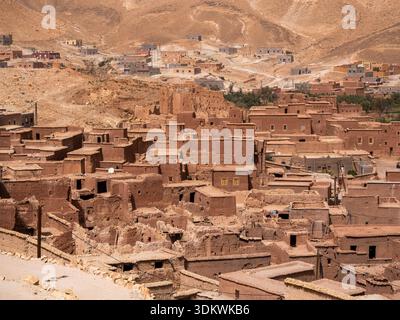 Tradizionale kasbah berbera fatta di mattoni di fango rosso che scendono lungo un arido pendio di montagna nel deserto nel sud del Marocco. Autentica architettura di terra e Foto Stock