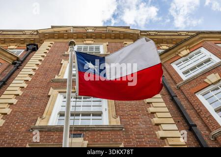 Bandiera cilena che sventola di fronte a un edificio in mattoni Foto Stock