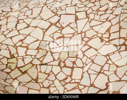 Sfondo astratto a mosaico trencadís con piastrelle di ceramica beige rotte incastonate in un caldo campo di terracotta. Foto Stock