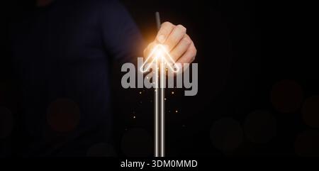 Concetto di crescita e successo. Un uomo disegna una freccia luminosa verso l'alto su sfondo scuro. Strategia aziendale, raggiungimento degli obiettivi, pianificazione degli obiettivi, sviluppo personale Foto Stock