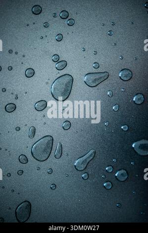Primo piano blu di gocce d'acqua su una superficie liscia, sfondo astratto con un'atmosfera pulita e rinfrescante Foto Stock