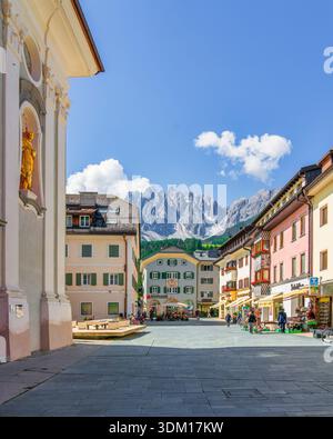 SAN CANDIDO, ALTO ADIGE - ITALIA - 27 GIUGNO 2024 Piazza pedonale centrale a San Candido, Innichen, con edifici alpini e vette dolomitiche Foto Stock