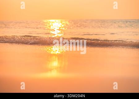 Tramonto dorato, il sole che si riflette sulle onde calme del mare sulla riva di una spiaggia tropicale. Oceano caldo e luminoso. Vacanze estive, viaggio, paradiso, luna di miele scenografica Foto Stock