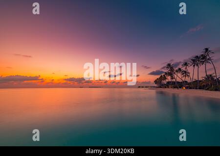 Trascinante tramonto viola arancione su una calma laguna tropicale con silhouette di palme. Bagliore vivido del cielo. Viaggio estivo vacanza luna di miele romanticismo paradiso panorama Foto Stock