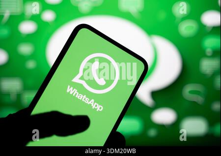 PARIGI, FRANCIA - 24 SETTEMBRE 2025: Sullo schermo di uno smartphone viene visualizzato il logo WhatsApp, su sfondo sfocato con le icone dei messaggi. Foto Stock