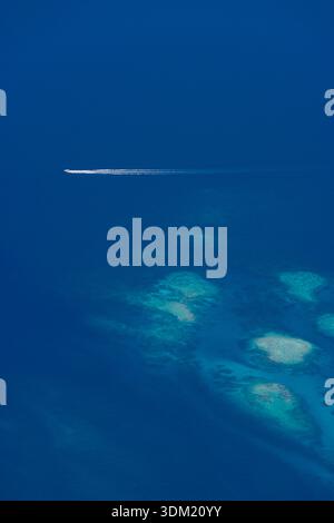 Vista aerea dall'alto di un oceano blu profondo con risveglio di barca e astratto di barriera corallina. Texture del mare azzurro. Vacanza estiva, spazio di copia minimo natura Foto Stock