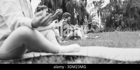 Donne che fanno esercizi di yoga all'aperto nel parco cittadino - stile di vita sano e concetto di sport - attenzione principale sul volto femminile asiatico - editing in bianco e nero Foto Stock