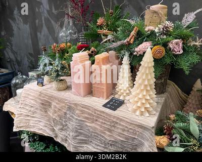 Londra, Regno Unito, 5 dicembre 2025, esposizione di candele natalizie con candele decorative a forma di torre di pesca rosa, candele bianche di panna sull'albero beige fabri Foto Stock