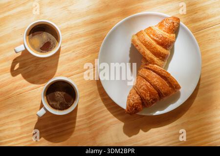 Due tazze espresso e croissant al sole del mattino Foto Stock