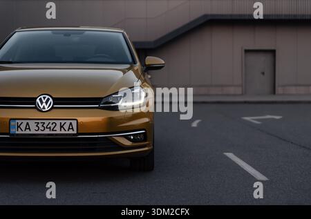 Lato anteriore sinistro del Volkswagen Golf sulla strada della città. Parte anteriore della moderna auto VW al crepuscolo, muro di edificio beige sullo sfondo. Foto Stock