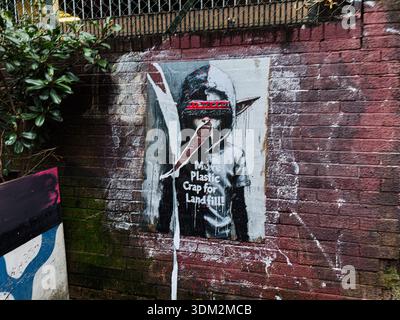 Manchester, Regno Unito - 21 gennaio 2026: Murale a figura con cappuccio a Manchester con messaggio di protesta su discariche e rifiuti. Foto Stock