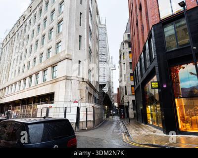 Manchester, Regno Unito - 21 gennaio 2026: Scena urbana di Manchester, Regno Unito, con costruzioni, vetrine e pavimentazioni bagnate. Foto Stock
