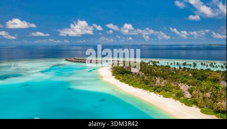 Vista aerea del lussureggiante resort tropicale dell'isola circondato da un oceano turchese mozzafiato delle Maldive, una destinazione paradisiaca esotica da sogno, un luminoso drone Foto Stock