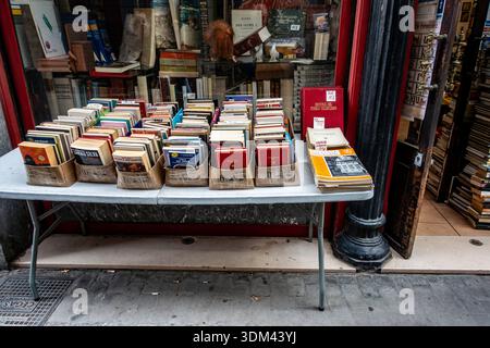 Libri di seconda mano in vendita su un tavolino all'esterno di El asilo del Libro, una storica libreria di Valencia, Spagna, con fascino e arte vintage. Foto Stock