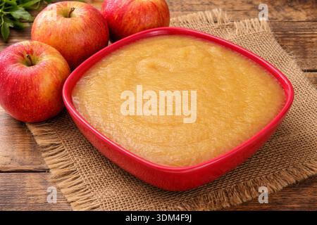 Salsa di mele fatta in casa in un recipiente rosso con mele fresche Foto Stock