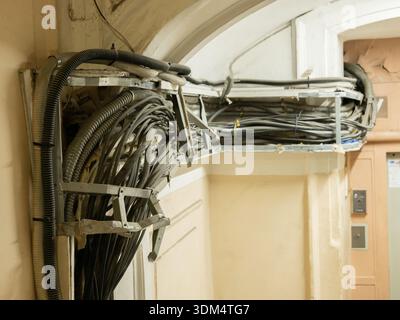 Groviglio di cavi elettrici e condotti in un vecchio edificio Foto Stock