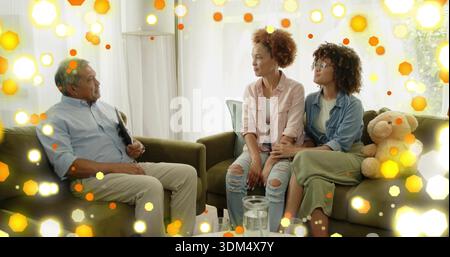 Uomo parlante in camicia blu che tiene la cartella, due donne sedute su divani verdi con orsacchiotto Foto Stock