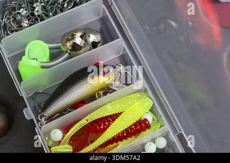 Scatola di attrezzatura da pesca aperta che mostra una collezione colorata di esche, esche e attrezzature. Questo contenitore in plastica ha maschere e ganci organizzati per la giornata di spor Foto Stock