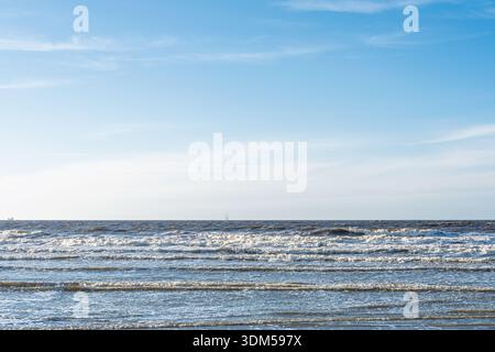 Gentle Waves on the Seashore sotto un cielo blu brillante. Ambiente tranquillo dell'oceano per rilassarsi Foto Stock