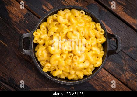 Cremoso mac e formaggio in una padella di ghisa su un tavolo in legno rustico - un comodo shot di cibo Foto Stock