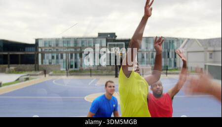 Raggiungi l'uomo con una t-shirt gialla atletica che cattura il rimbalzo vicino al cerchio sul campo blu all'aperto Foto Stock
