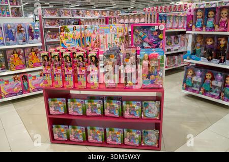 Ampia vista su un corridoio di un negozio di giocattoli con bambole Barbie e giocattoli per bambini esposti sugli scaffali in un luminoso ambiente di vendita al dettaglio. Foto Stock
