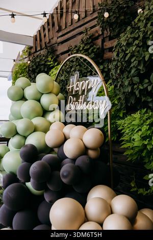 Cartello al neon Happy Birthday con arco a palloncino verde e decorazioni per feste all'aperto Foto Stock