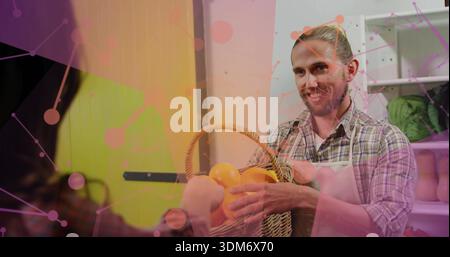 Offre un fornitore barbuto che consegna cesto di arance intrecciato dietro il bancone del mercato, grembiule a quadri Foto Stock