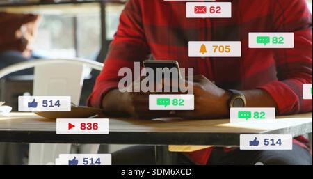 Controllare lo smartphone, l'uomo con la camicia rossa e guardare appoggiarsi al tavolo del caffè con le notifiche Foto Stock