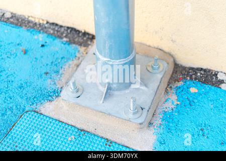 Piastra di base per palo in metallo con bulloni di ancoraggio su pavimento in calcestruzzo Foto Stock